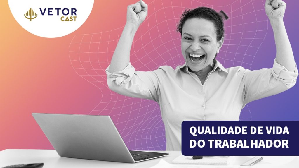 Mulher com expressão de felicidade em frente a uma mesa de escritório e, sobre a mesa, um notebook aberto.