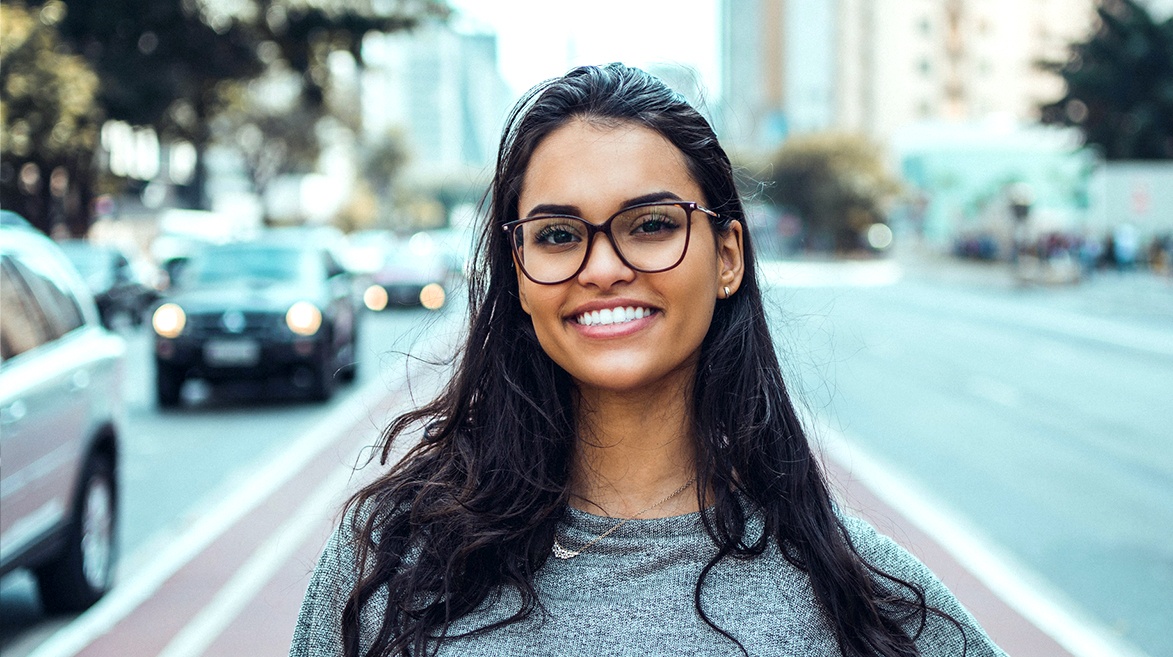 Foto de uma mulher de cabelo longo e óculos preto, no centro da ciclofaixa da Avenida Paulista